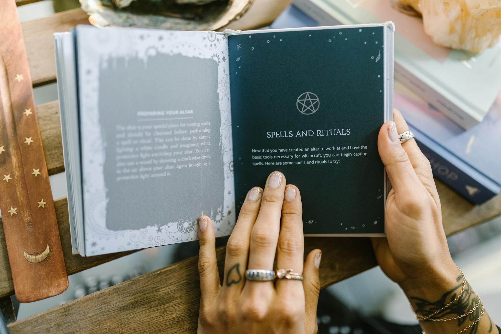 Close-up of hands holding an open book about spells and rituals, featuring a pentagram symbol.